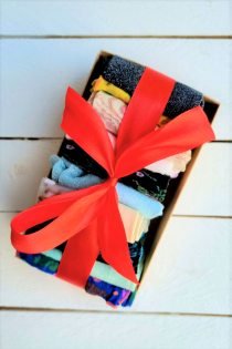 Gift box with ten pairs of women's socks in various colors and patterns, tied with a red satin ribbon.
