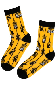 Yellow BURTON socks with black Halloween patterns, like skeletons and cityscapes, featuring black heels and toes.