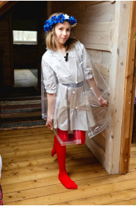 Transparent children's raincoat with red leggings. Blue flower crown on head.