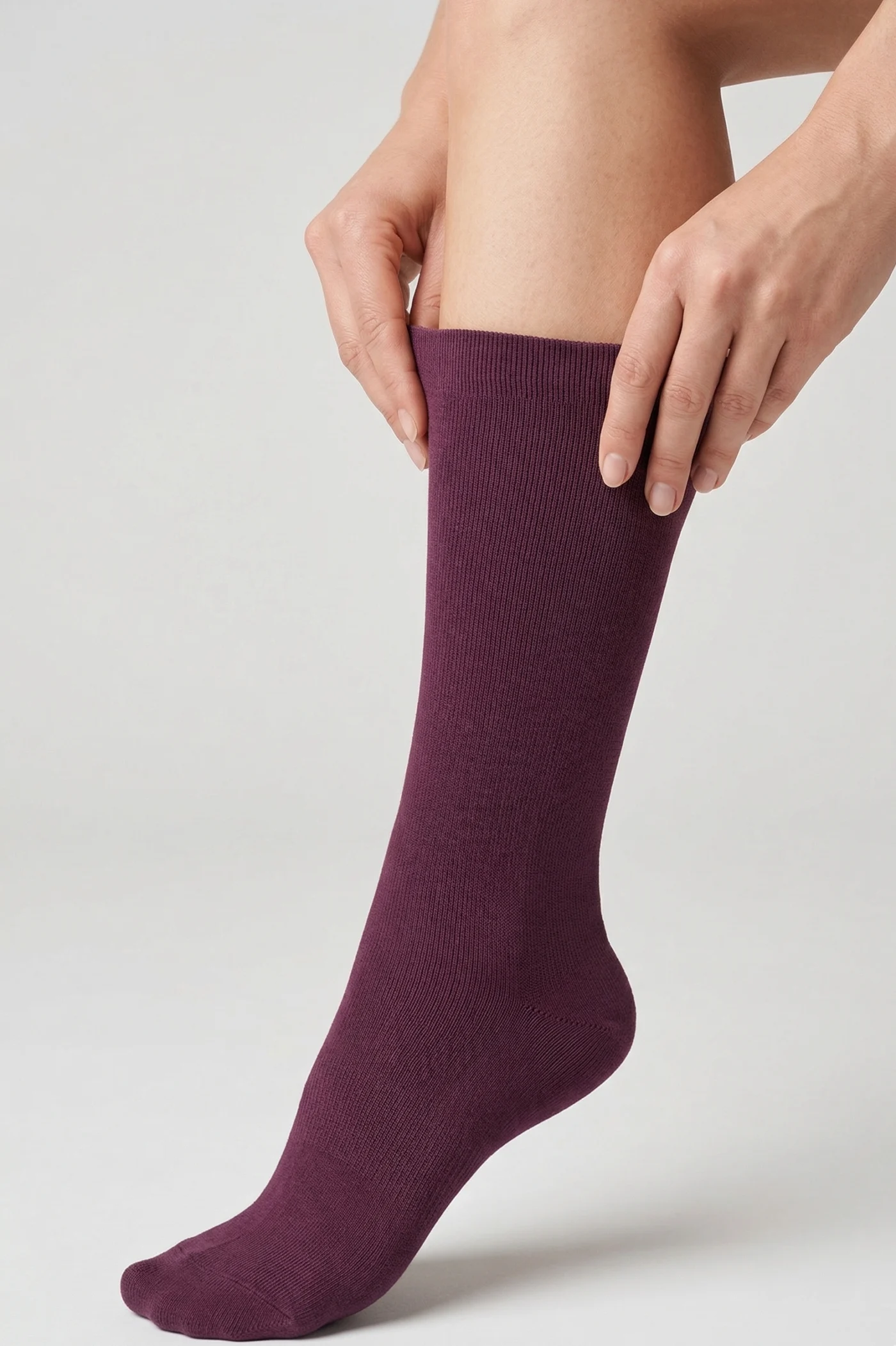 Person putting on a purple compression sock, illustrating compression socks benefits for swelling relief and leg comfort.